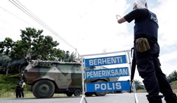 Anggota polis mengawasi kereta perisai pasukan tentera darat yang memasuki Jalan Tanjung Labian, di Felda Sahabat dalam usaha untuk mengetatkan lagi kawalan